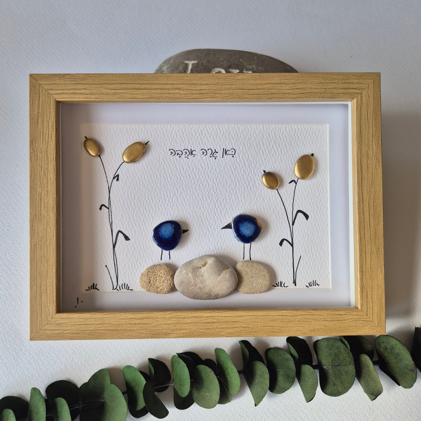 כאן גרה אהבה – יצירת קיר באבני קרמיקה כחולות וקני סוף מוזהבים